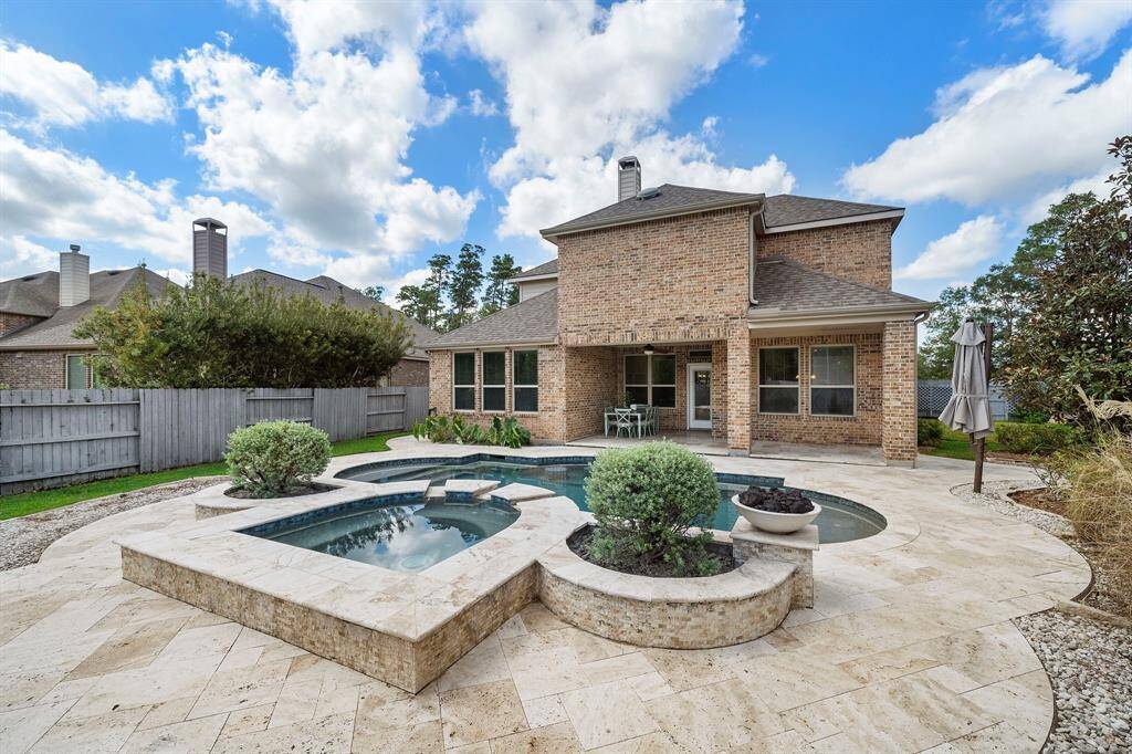 The oversized hot tub has a water feature that spills over into the pool.