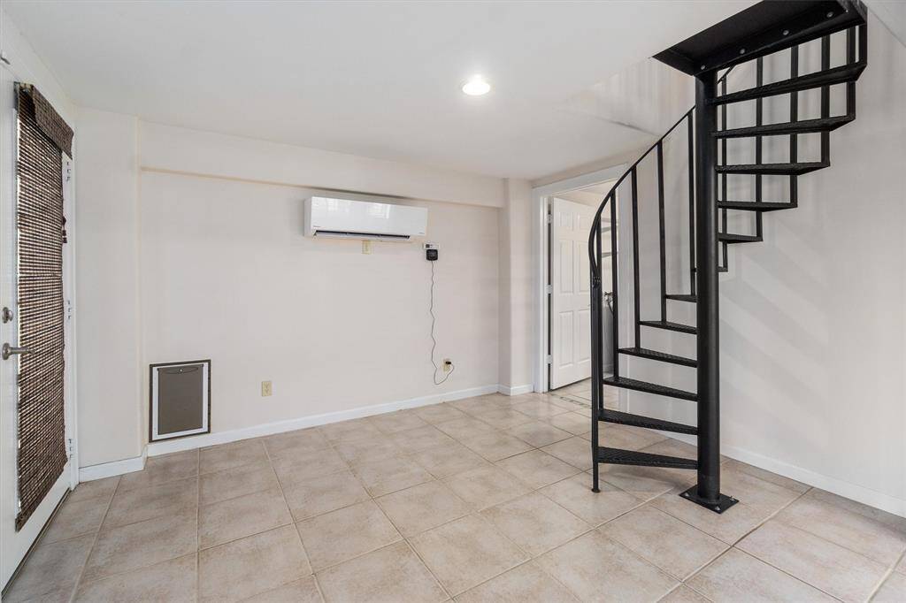 Spiral stairs to downstairs entertaining area. This area could be an office. Notice the mini split AC system that was replaced in 2024