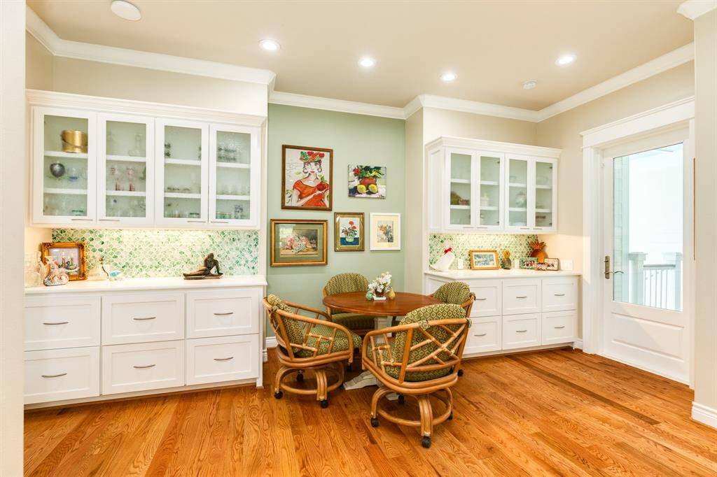 This is a cozy breakfast nook featuring built-in white cabinetry with glass front upper cabinets and ample drawer space below has a small seating area, perfect for casual dining or enjoying morning coffee.