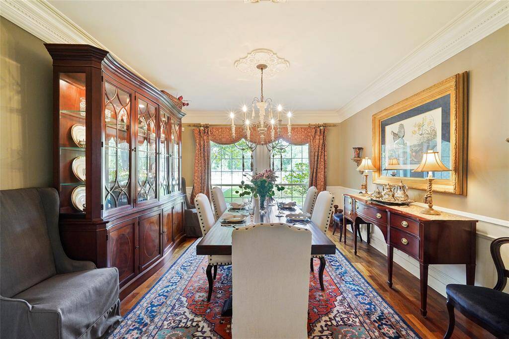Next to the office is the formal dining w/ double crown molding, hardwood floors & wainscoting