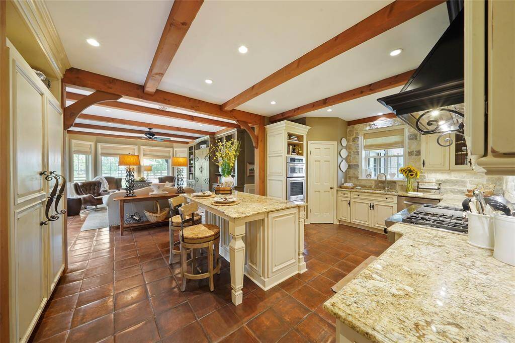 Saltillo tile floors run from the kitchen into the family room. Kitchen features a built-in Thermador fridge w/ cabinet panel doors for a seamless look!