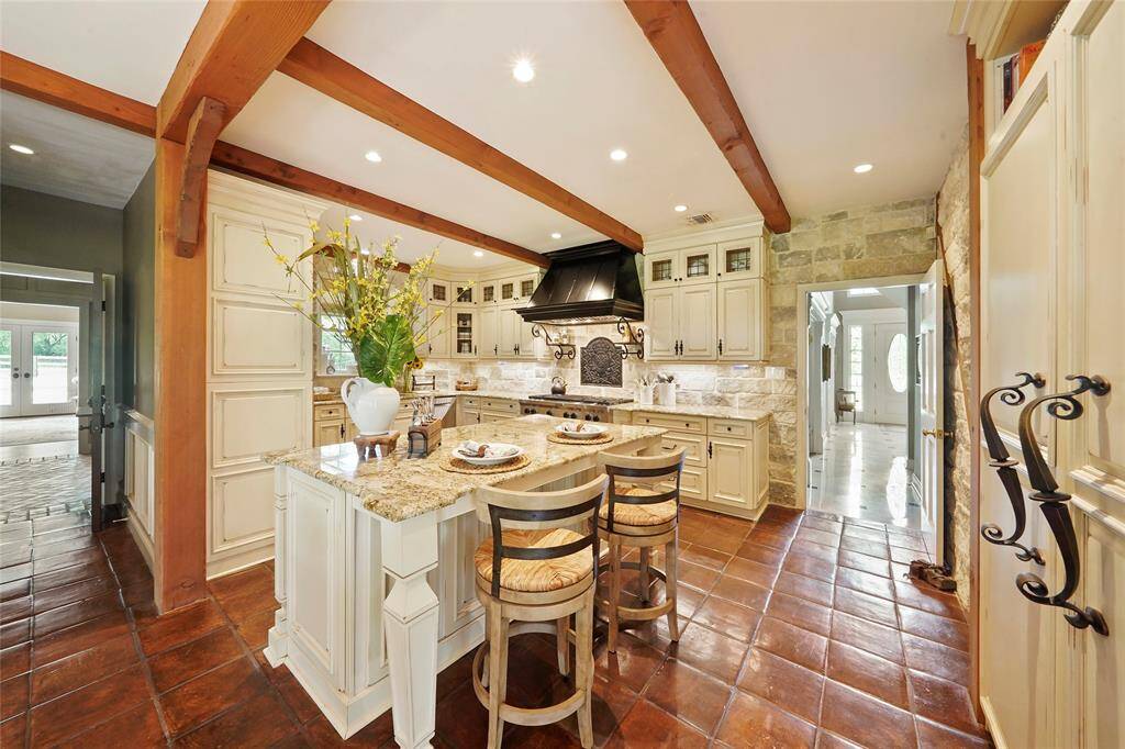 Remodeled kitchen features a large island & a limestone wall.