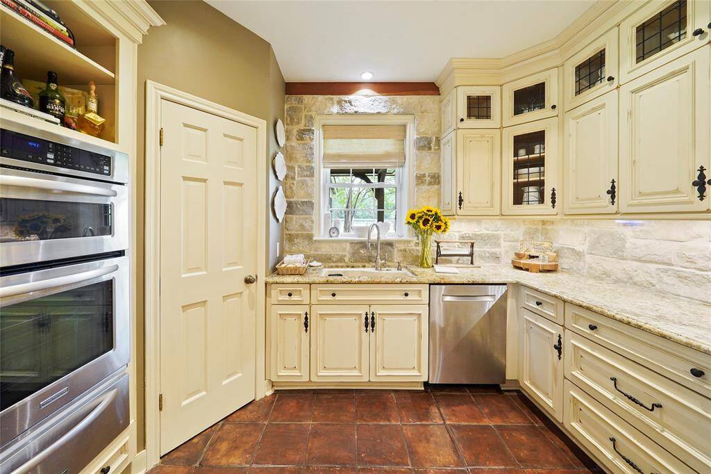 Stunning kitchen with modern stainless steel appliances, elegant granite countertops, and charming off-white cabinetry.