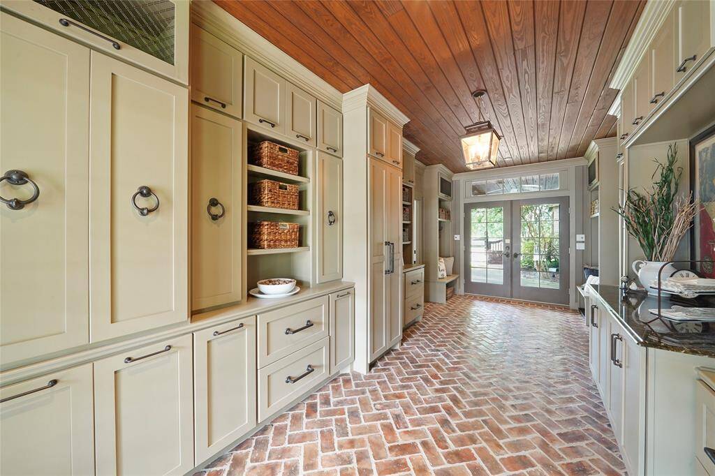 Btwn the family room & the gym, lies the back entry room. French doors open to the pool.