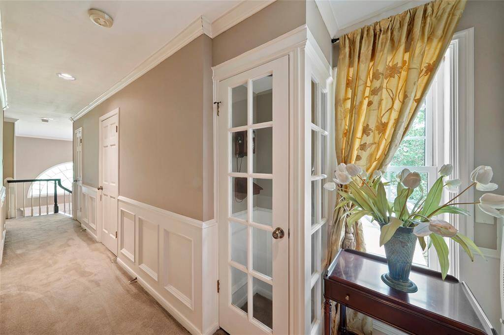 Elegant hallway featuring a charming window view, classic white trim, and a beautiful tulip arrangement.
