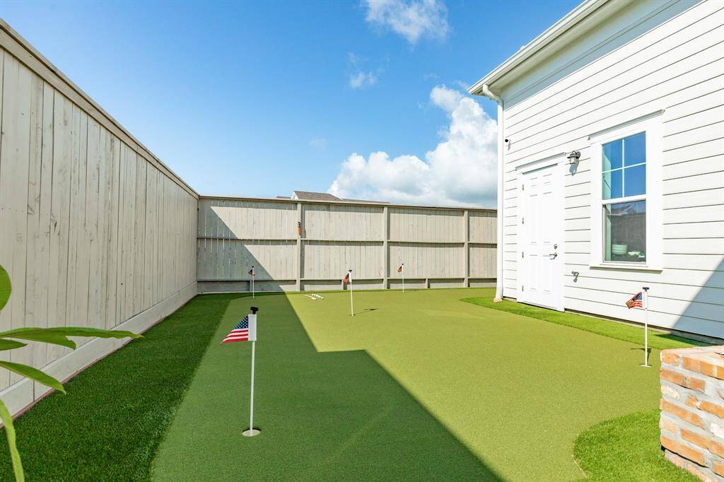 Another view of putting green in fenced backyard.