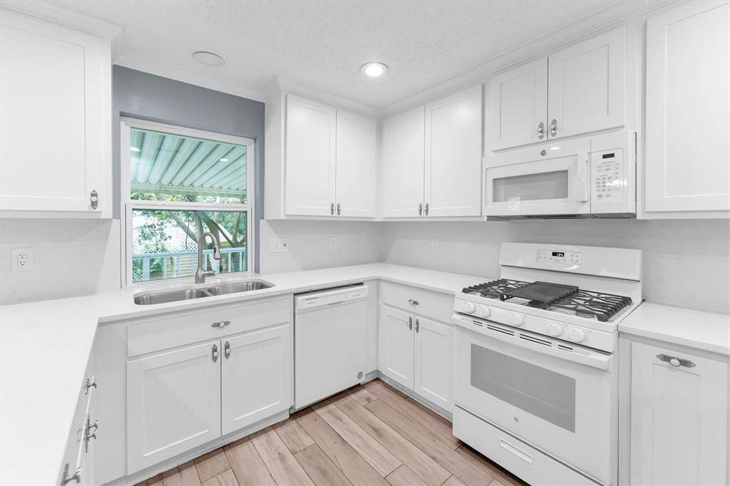A modern kitchen featuring clean cabinetry and updated appliances, including a microwave and gas stove.