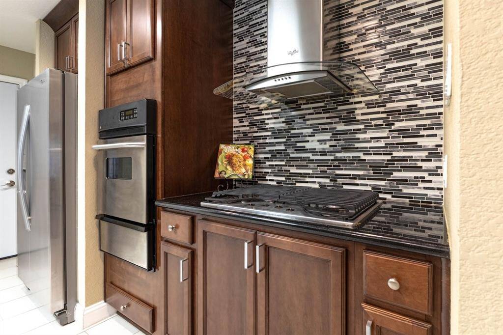 Modern kitchen featuring rich wooden cabinetry, and a stylish mosaic backsplash.