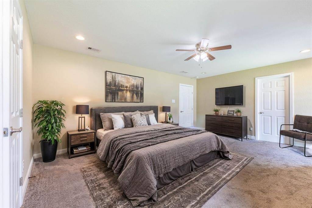 *Virtually Staged*This is a spacious, well-lit primary bedroom featuring a ceiling fan, and this room includes carpeted flooring, a tasteful color scheme, and has both a window and an en-suite door, offering convenience and comfort.