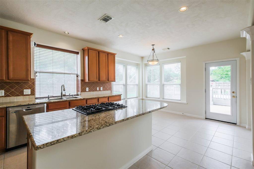 A spacious kitchen featuring with a large granite countertop, downdraft gas cooktop, ample cabinet space, perfect for social gathering cooking