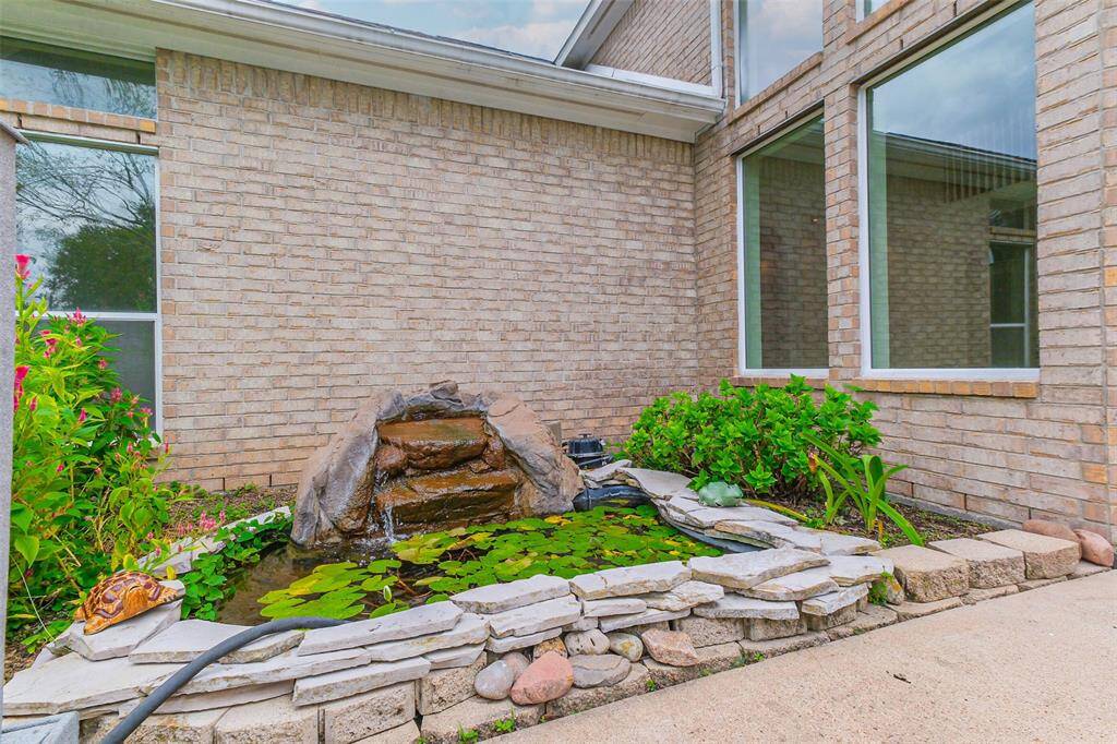 A fishpond with a gentle waterfall, surrounded by nature, creates a tranquil and relaxing atmosphere