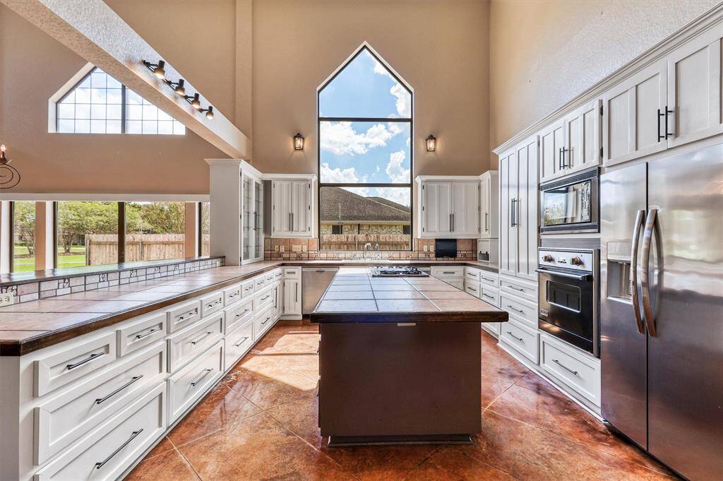 Chef's Dream Kitchen with island. Refrigerator included. Display your favorite dishes in the glass cabinet. Abundant amount of cabinets and drawers.