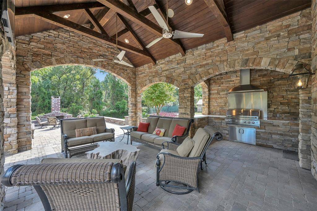 Covered patio with outdoor kitchen, conveniently located near fireplace and pool areas.