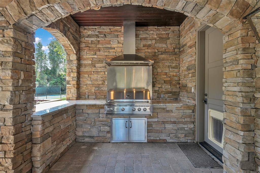Outdoor kitchen area with granite countertops. Bar seating on the outside of the opening. Door to the right is access to half bathroom.