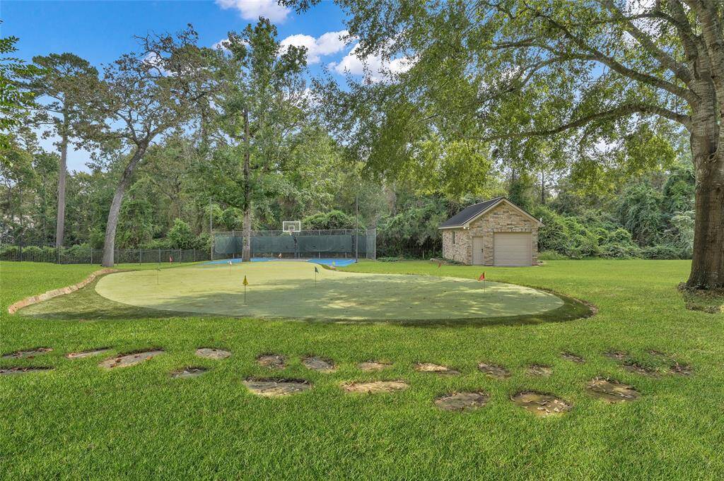 Enjoy a 9-hole putting green or the lighted sports court. To the right, you'll find a workshop equipped with a mini-split A/C, currently set up as a golf simulator.