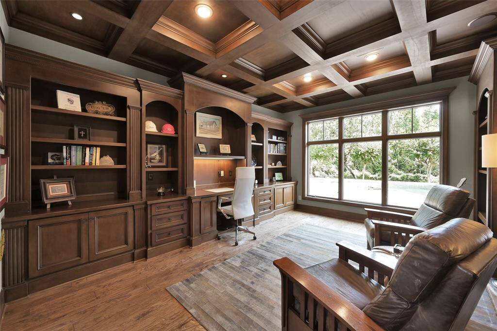 Spacious office featuring custom built-in cabinetry, a coffered ceiling, and a view of the pool.