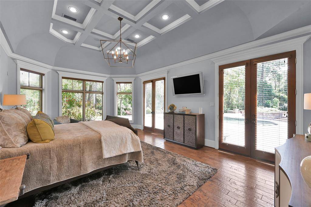 Primary bedroom featuring a coffered ceiling and plenty of windows. French doors open to the pool and backyard.
