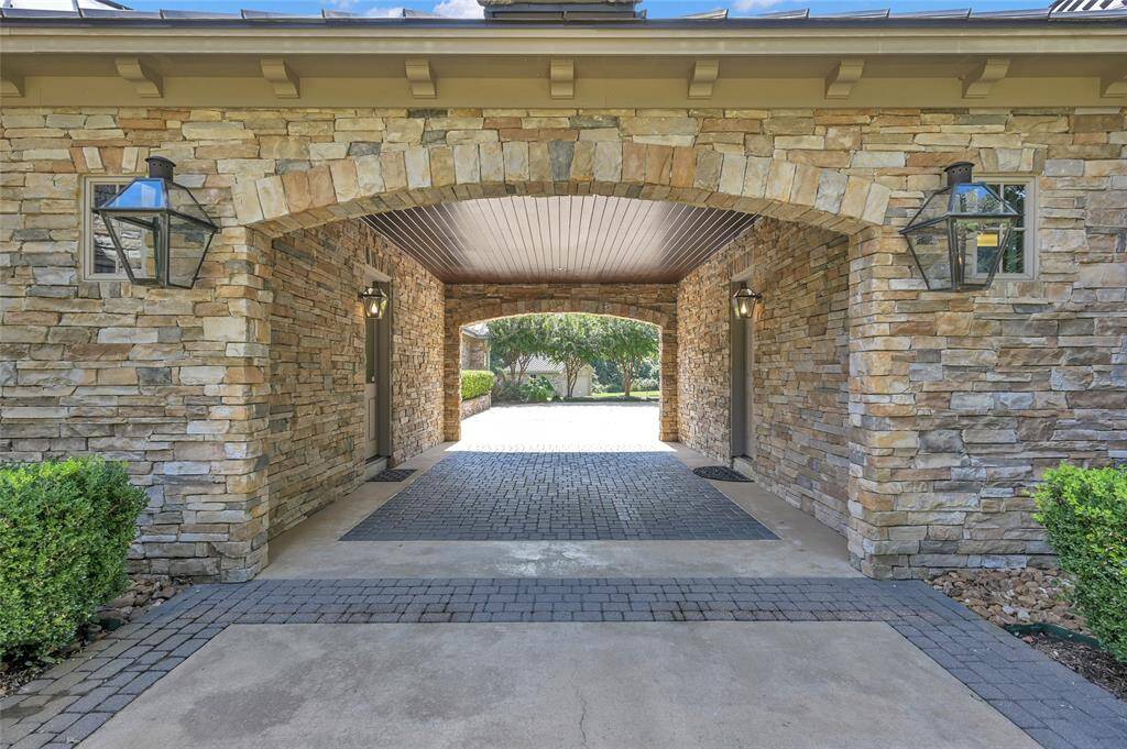 The porte-cochere links the home to the four-car garage, enhanced by gas lanterns and charming paver details.