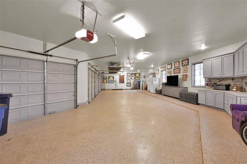 Oversized four-car garage featuring built-in cabinets for added storage.