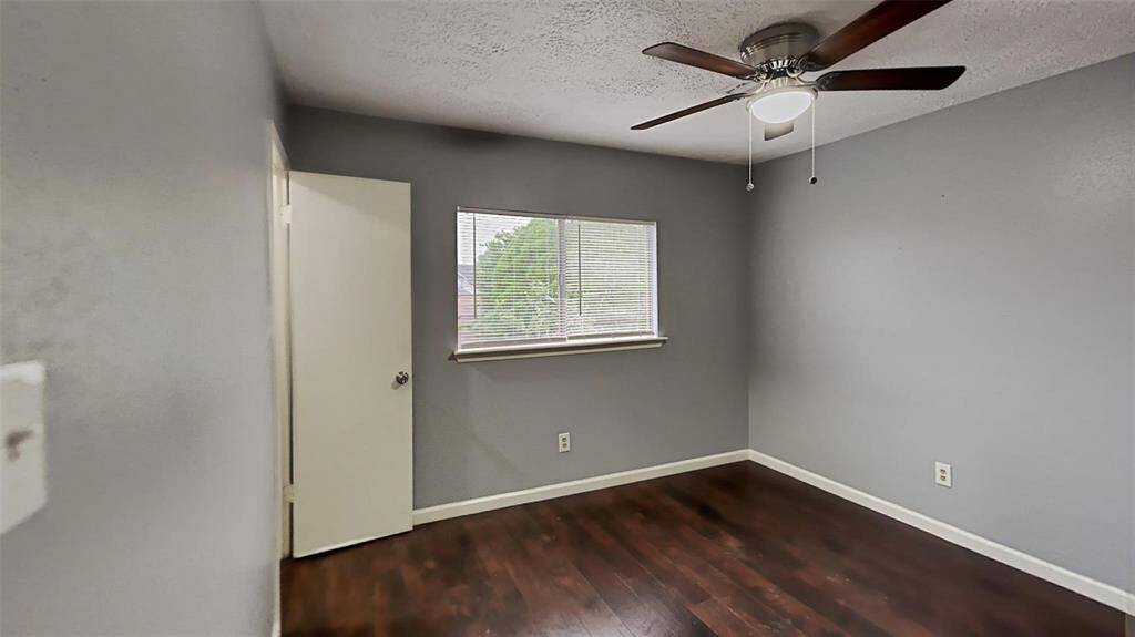 Cozy Retreat: This serene bedroom offers a tranquil space with ample natural light, elegant hardwood floors, and a modern ceiling fan for comfort.