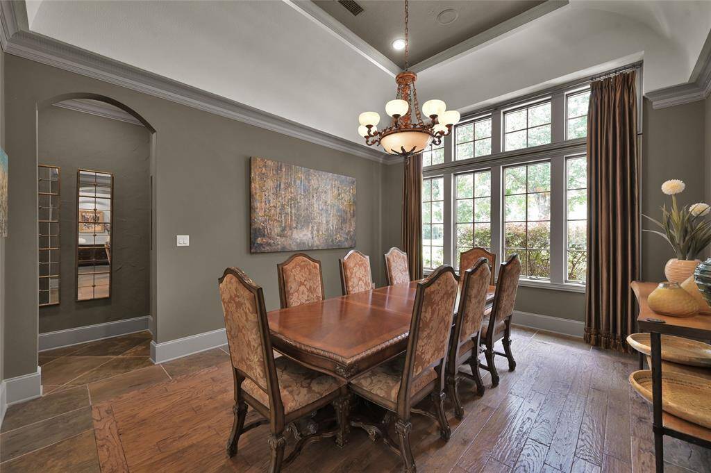Formal dining room featuring elegant wood inset flooring, a spacious window, and soaring vaulted ceilings.