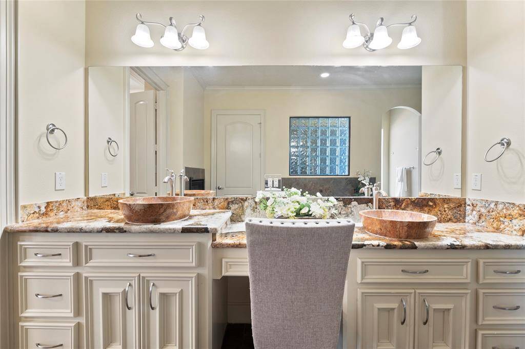 The bathroom features a well-appointed design with double sinks, and dedicated vanity station enhancing the functionality of the space, offering ample storage through thoughtfully designed cabinets and drawers.