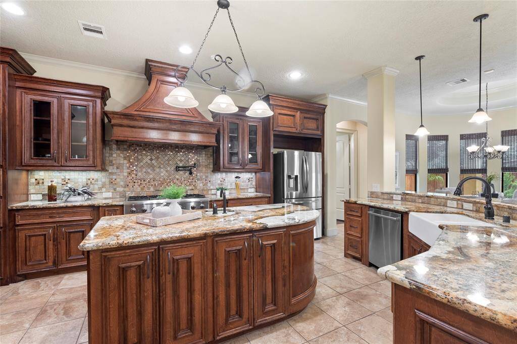 An additional island with a small sink, custom wood cabinetry and range hood, this kitchen blends functionality and style.