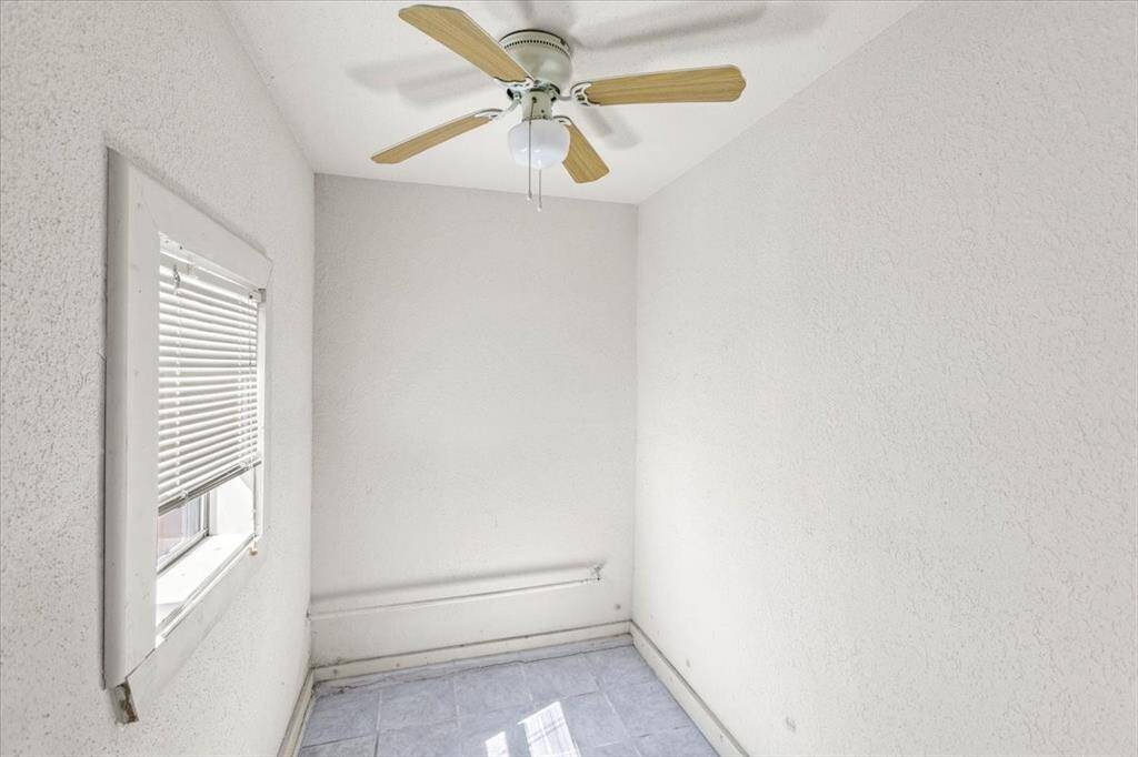 This office space is well-lit with a ceiling fan and a single window.