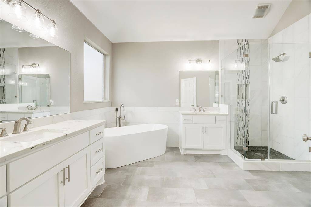 SPA-QUALITY MASTER BATHROOM OFFERS UPDATED DUAL SINKS, SOAKING TUB, AND A GLASS ENCLOSED WALK-IN SHOWER.