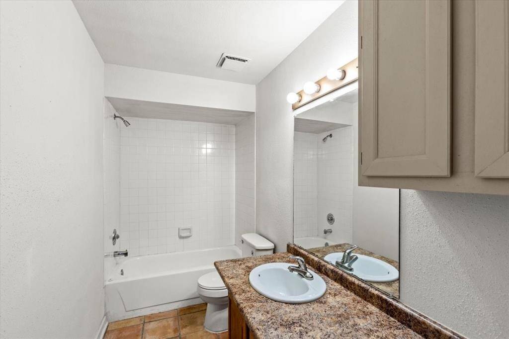 This is a well-lit hallway bathroom with tub/shower combo and single vanity.