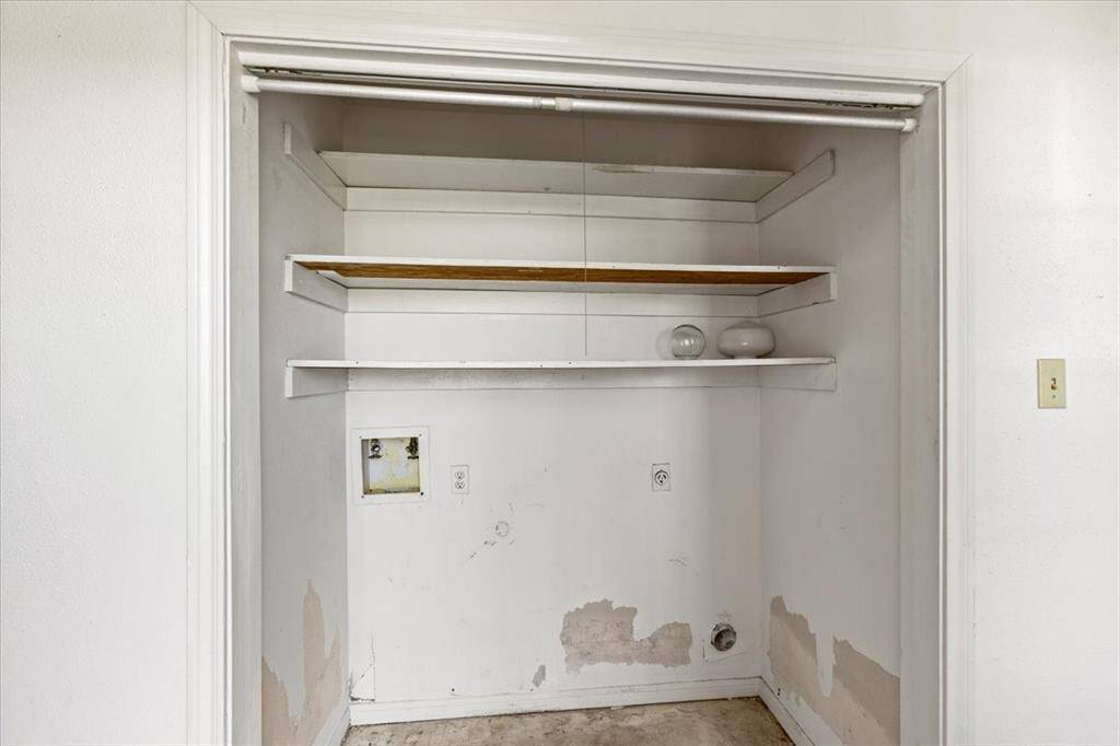 This is a utility space with shelving in need of cosmetic updates, featuring hookups for full sized washer & dryer.