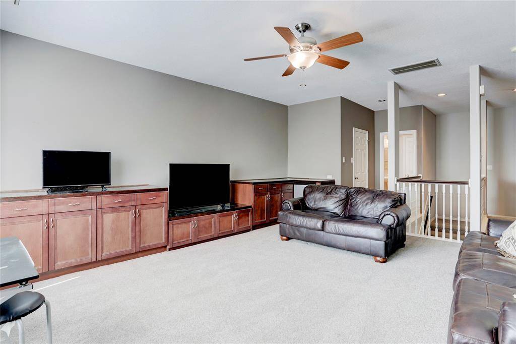 HUGE UPSTAIRS GAMEROOM FEATURING PLUSH CARPETING, EXPANSIVE BUILT-IN CABINETRY WITH AMPLE STORAGE MAKING IT A PERFECT SPACE FOR RELAXATION OR ENTERTAINMENT.
