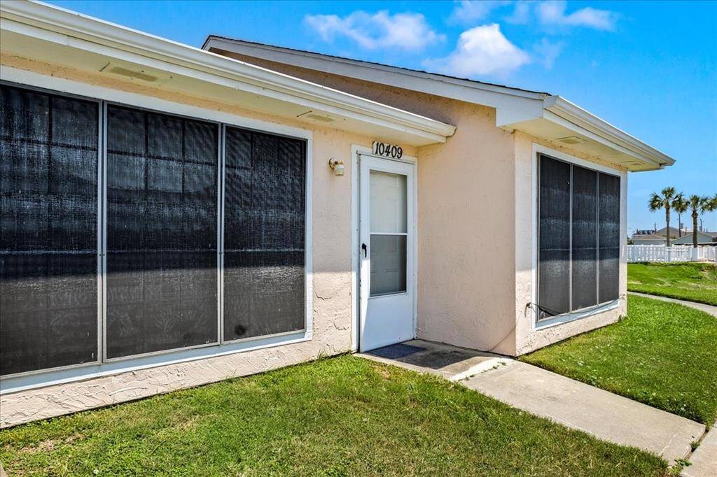 This is a single-story townhome featuring a clean, maintained front yard, large windows with sun screens, and a welcoming front door.