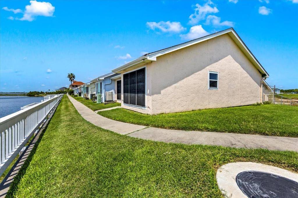 This is a single-story waterfront townhome featuring a well-maintained lawn and a fence along the water's edge, offering a serene view and a sense of privacy.
