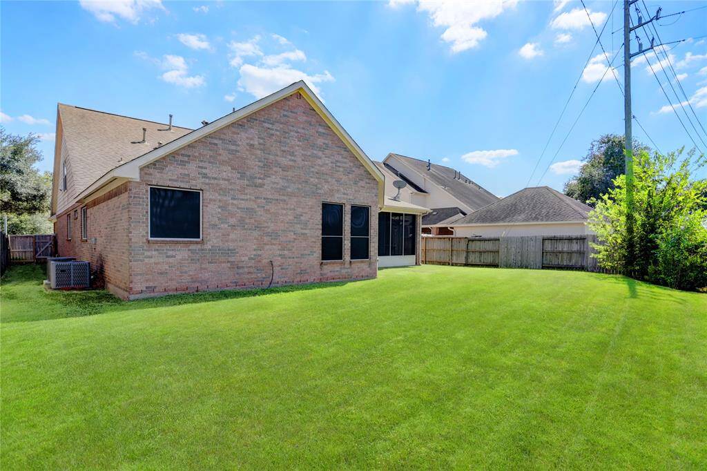 A SPACIOUS BACKYARD FEATURING LUSH GREEN GRASS AND A LOW MAINTENANCE LAYOUT EQUIPPED WITH A SPRINKLER SYSTEM.
