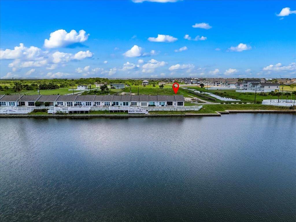 This is an aerial view of a row of waterfront townhouses with a clear view Campeche Cove Lake, showcasing a serene suburban setting.