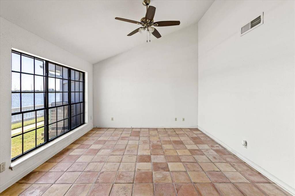 This is a bright, airy living room featuring large windows with black frames, offering a view and plenty of natural light. The space appears ready for personalization by the new homeowner.