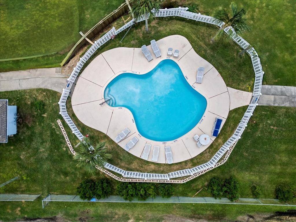 This aerial photograph showcases the kidney-shaped community pool with a well-maintained surrounding deck and multiple lounge chairs.