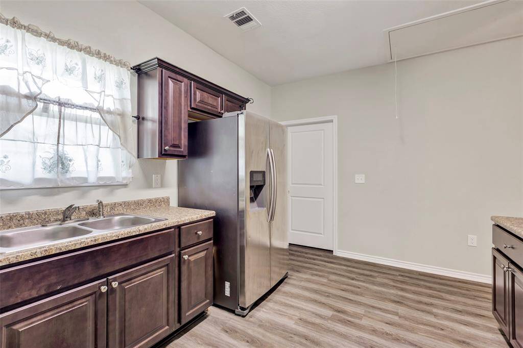 This view showcases additional cabinetry for ample storage, along with a bright glass window above the double sink that brings in natural light and enhances the kitchen's feel.