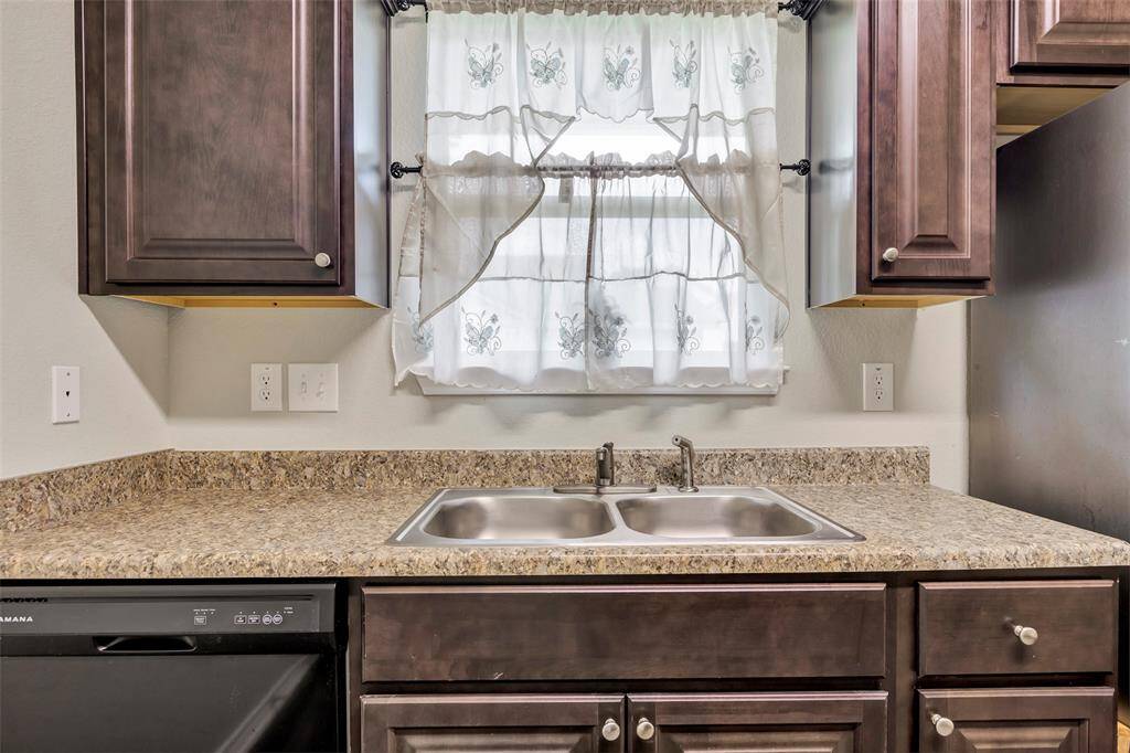 This close-up of the kitchen highlights the sleek granite countertop, with several conveniently placed outlets along the wall, perfect for all your kitchen appliances.