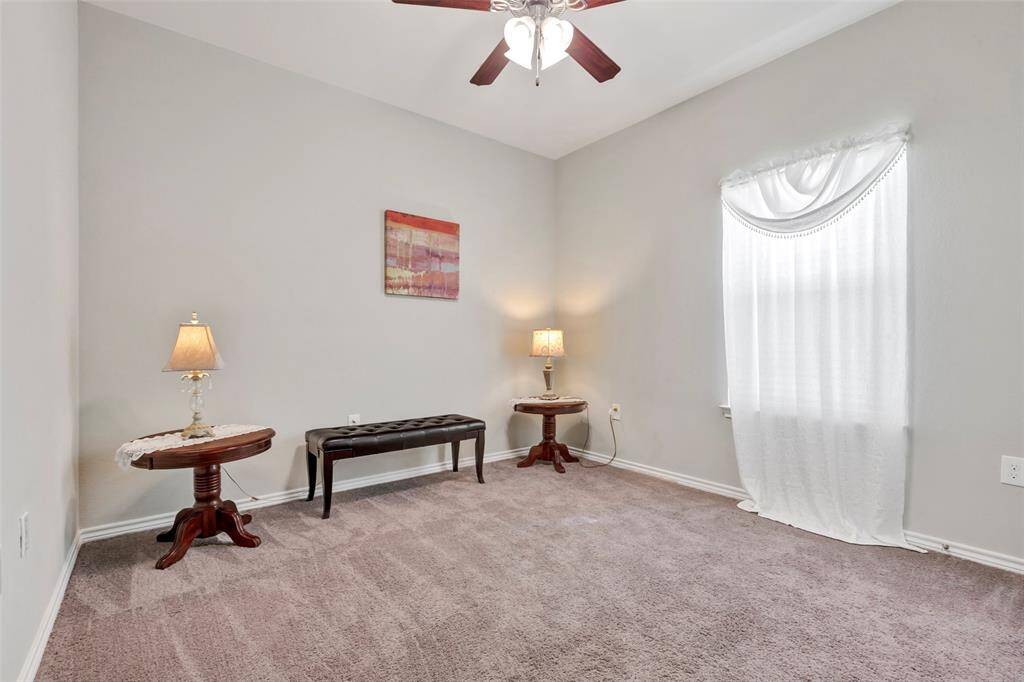 The secondary bedroom features a cozy carpeted floor, a ceiling fan for comfort, and a bright glass window that invites natural light.