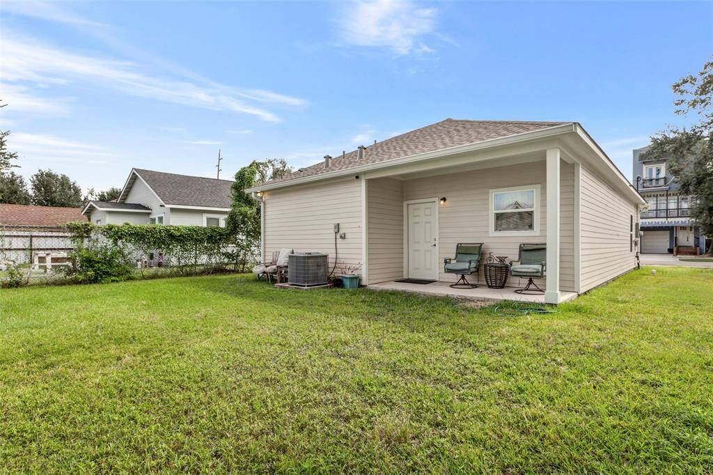 This charming back covered patio offers a serene retreat, perfect for relaxation with views of the lush green backyard.