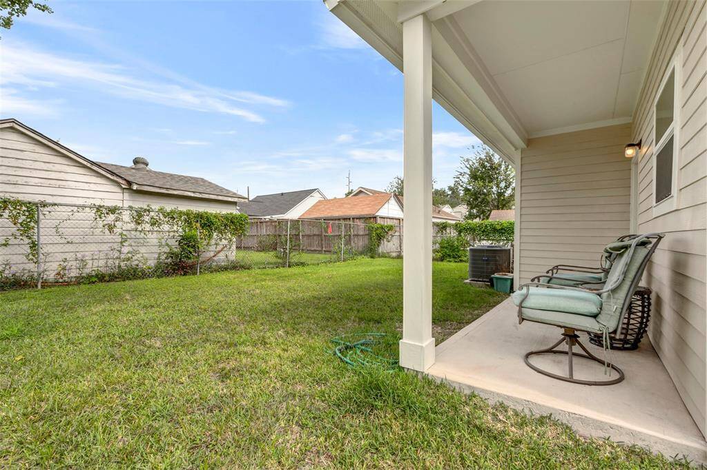 This charming back covered patio offers a serene retreat, perfect for relaxation with views of the lush green backyard.