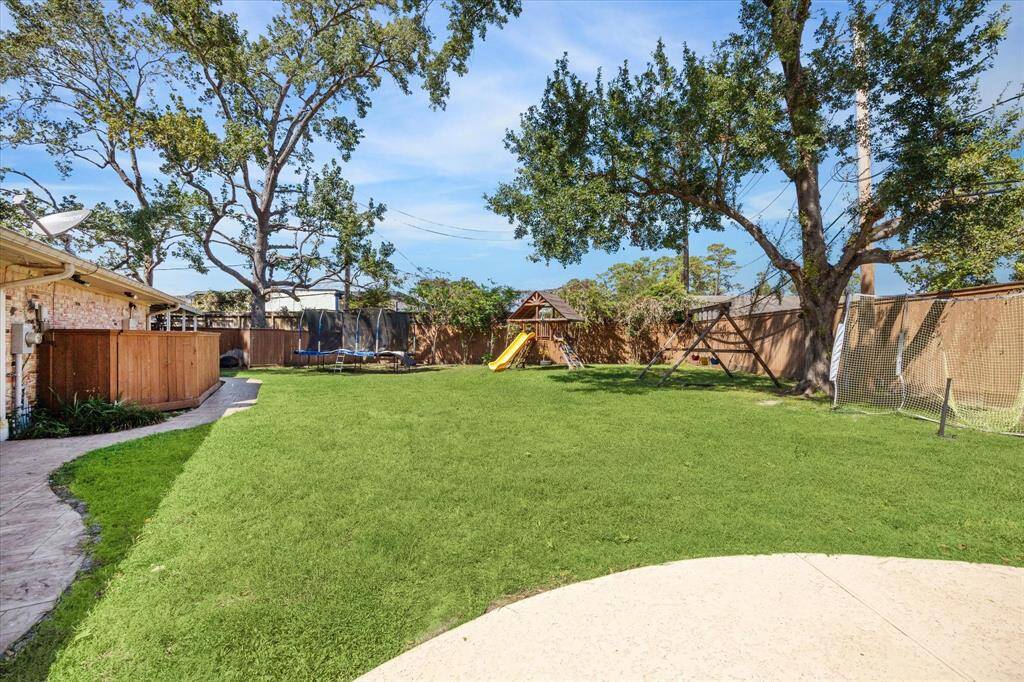 Backyard looking back to swing set, fort and trampoline