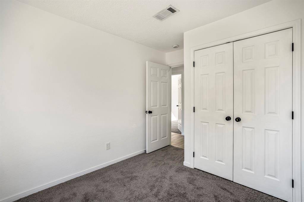 This inviting first bedroom features plush brand-new carpeting and a spacious closet adorned with sleek black hardware, offering both style and functionality. The fresh updates and modern finishes create a cozy and refined atmosphere.