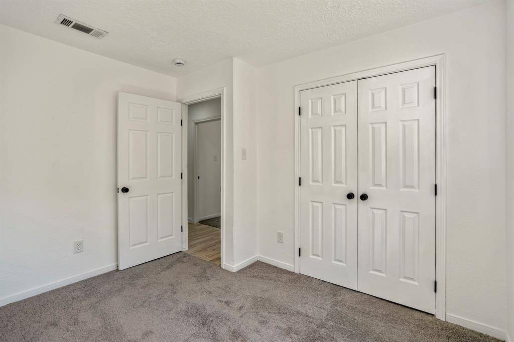 This third bedroom features brand-new, plush carpeting and a generously sized closet with sophisticated black hardware, blending practicality with a touch of modern elegance.