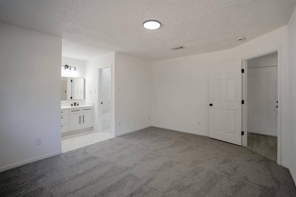 The primary bedroom offers a glimpse of the attached en suite bathroom, enhancing the room’s luxurious feel. With brand new carpet underfoot and a large walk-in closet, this space provides both comfort and convenience. The seamless connection to the en suite bathroom makes for an ideal private retreat.