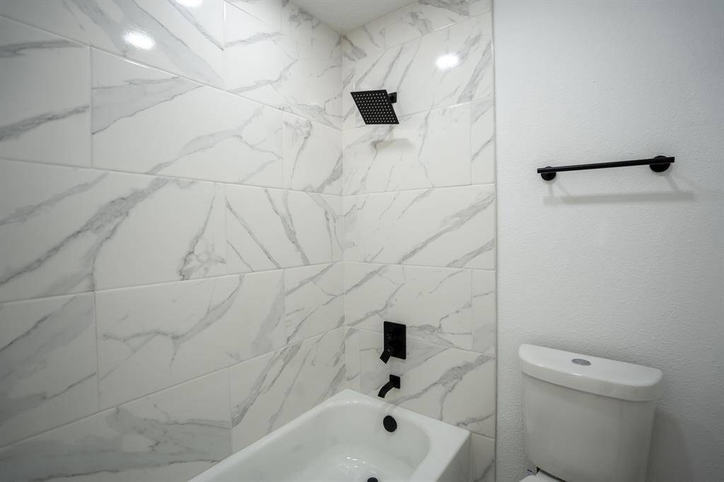 This view showcases the marble-look tile, perfectly paired with a sleek modern showerhead and matte black hardware. The refined tile adds texture and luxury to the space, while the bold black accents create a stylish, cohesive aesthetic.