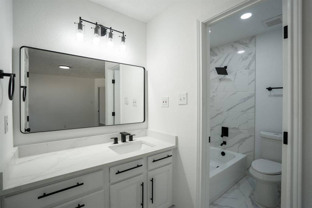 This master en suite bathroom features a stunning quartz countertop and sophisticated matte black hardware, combining elegance and modern design for a luxurious retreat.