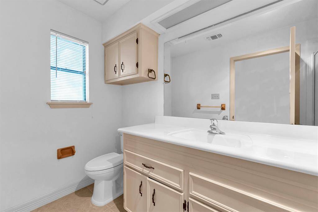 This bathroom has a large vanity with plenty of storage, a wall-mounted mirror, and a toilet.